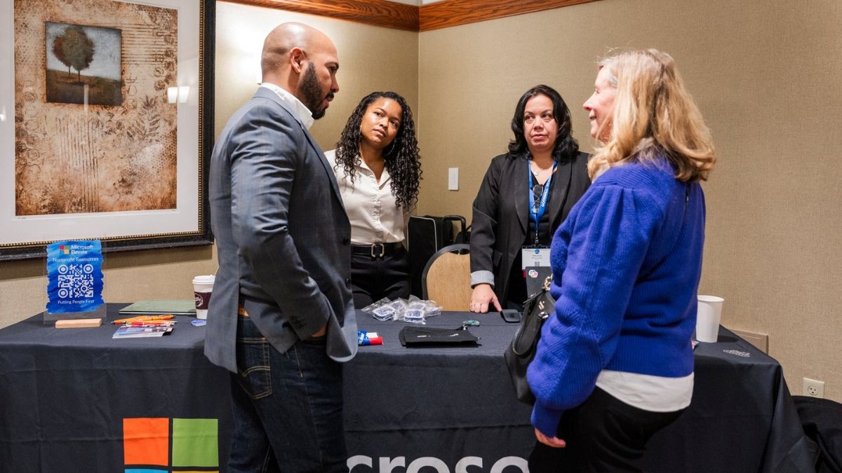 Attendees and representatives engaging at sponsor booth during corporate summit in Central PA